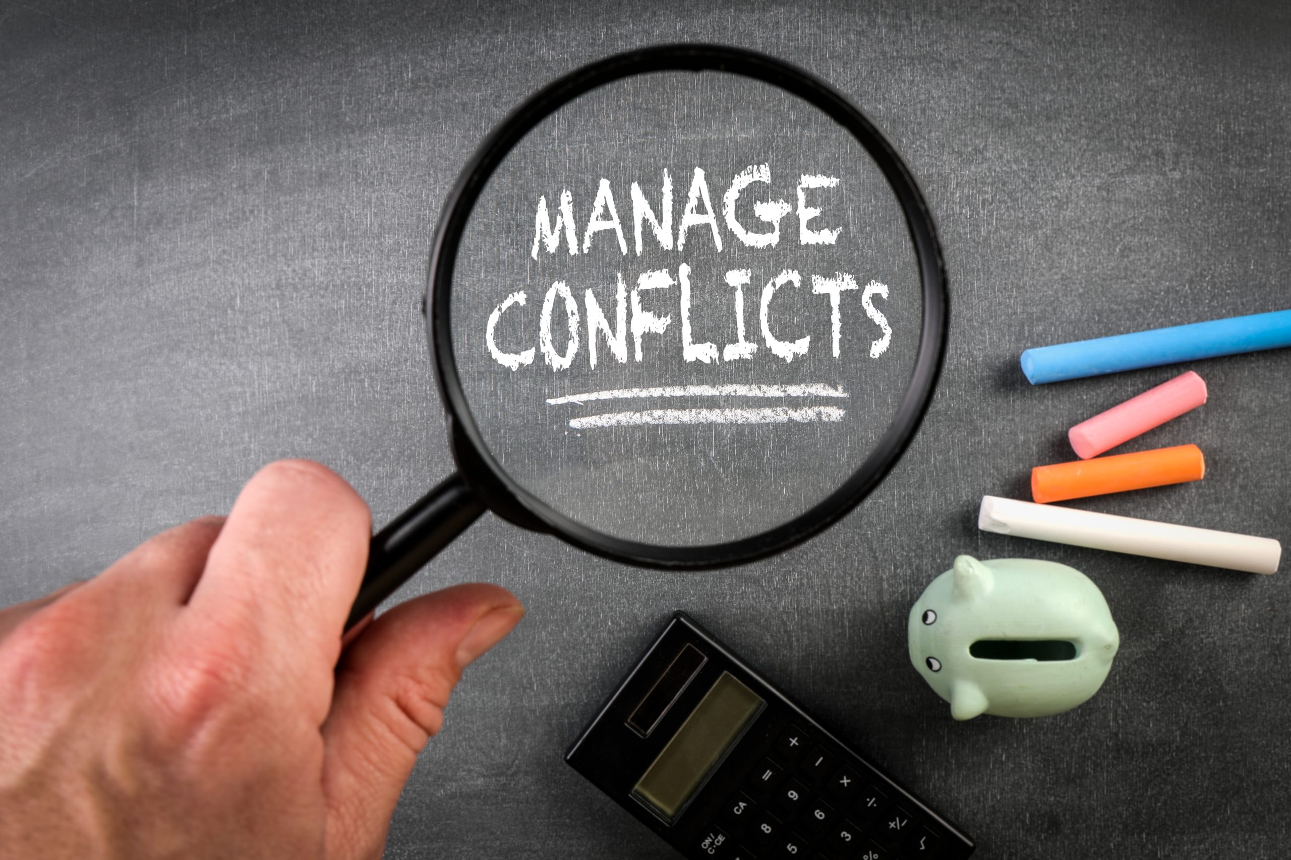 manage,conflicts.,text,and,magnifying,glass,on,a,blackboard.